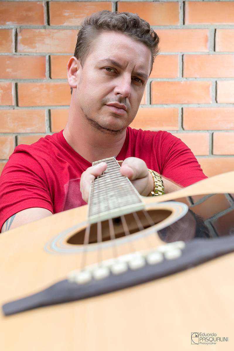 Homem segurando violão pelo braço do violão. Foto de Eduardo Pasqualini, fotógrafo de casamentos e ensaios em Rio do Sul, Santa Catarina.