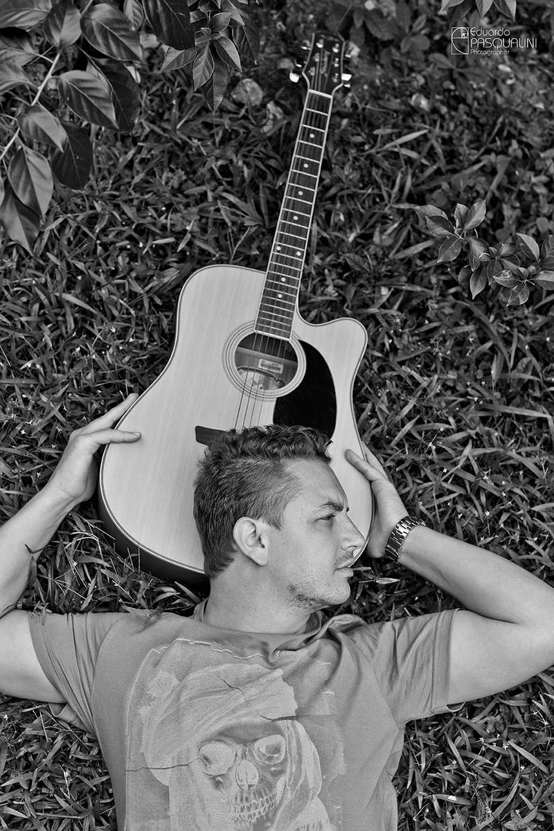 Homem deitado na grama com a cabeça apoiada no violão. Foto de Eduardo Pasqualini, fotógrafo de casamentos e ensaios em Rio do Sul, Santa Catarina.