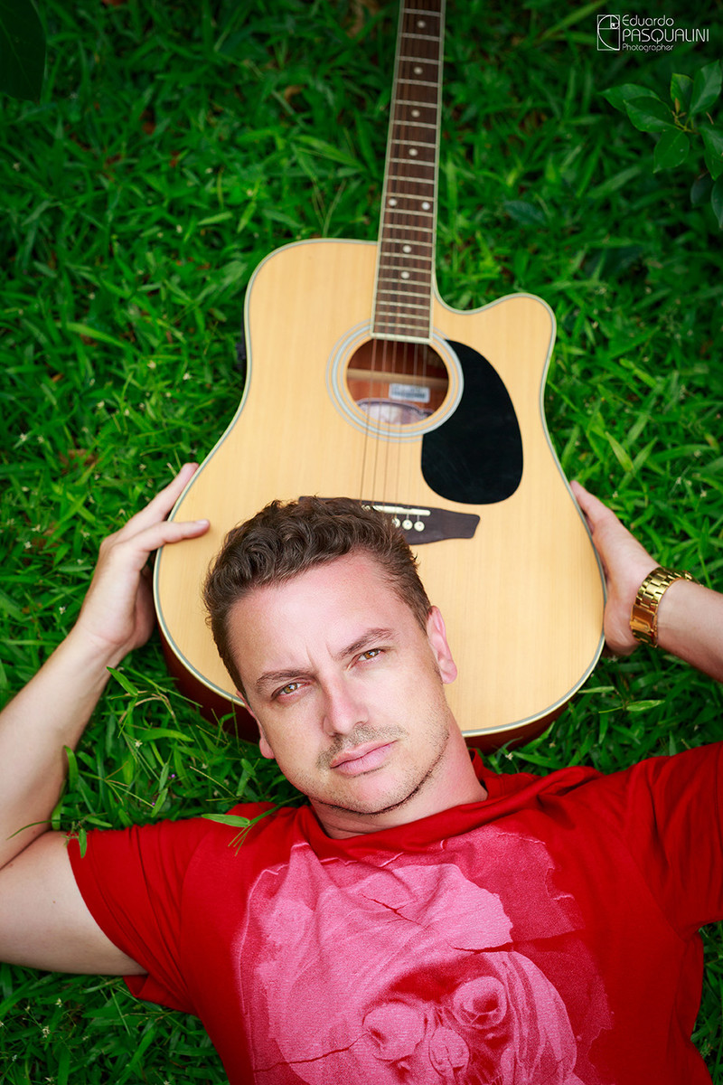 Foto de Homem deitado na grama com a cabeça apoiada no violão. Foto de Eduardo Pasqualini, fotógrafo de casamentos e ensaios em Rio do Sul, Santa Catarina.