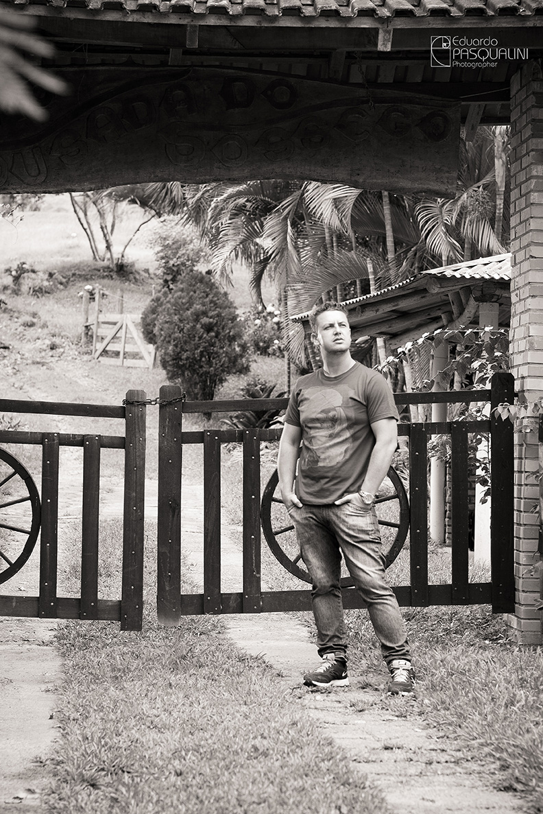 Homem em frente porteira, portão de sítio com as mãos no bolso. Foto de Eduardo Pasqualini, fotógrafo de casamentos e ensaios em Rio do Sul, Santa Catarina.