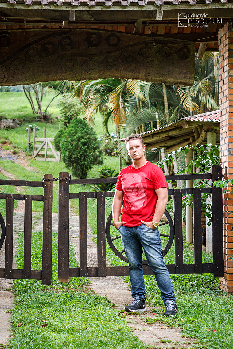 Homem em frente porteira, portão de sítio com as mãos no bolso. Foto de Eduardo Pasqualini, fotógrafo de casamentos e ensaios em Rio do Sul, Santa Catarina.
