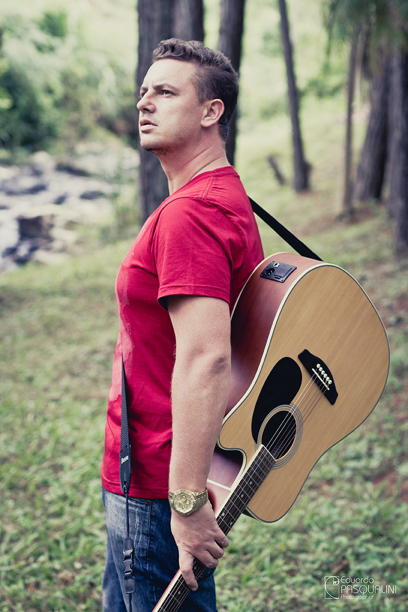 Homem com violão acústico nas costas em meio a natureza. Foto de Eduardo Pasqualini, fotógrafo de casamentos e ensaios em Rio do Sul, Santa Catarina.