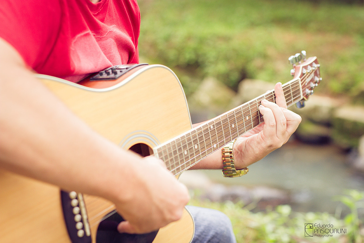 Mãos cotando violão acústico em meio a natureza. Foto de Eduardo Pasqualini, fotógrafo de casamentos e ensaios em Rio do Sul, Santa Catarina.
