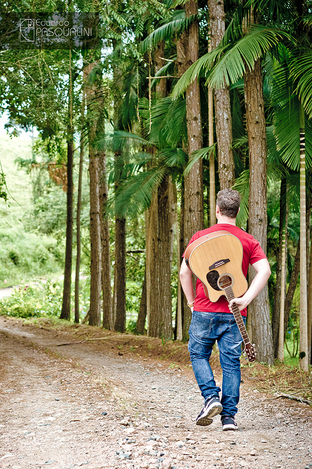 Andando com um violão nas costas em uma estrada de chão. Foto de Eduardo Pasqualini, fotógrafo de casamentos e ensaios em Rio do Sul, Santa Catarina.