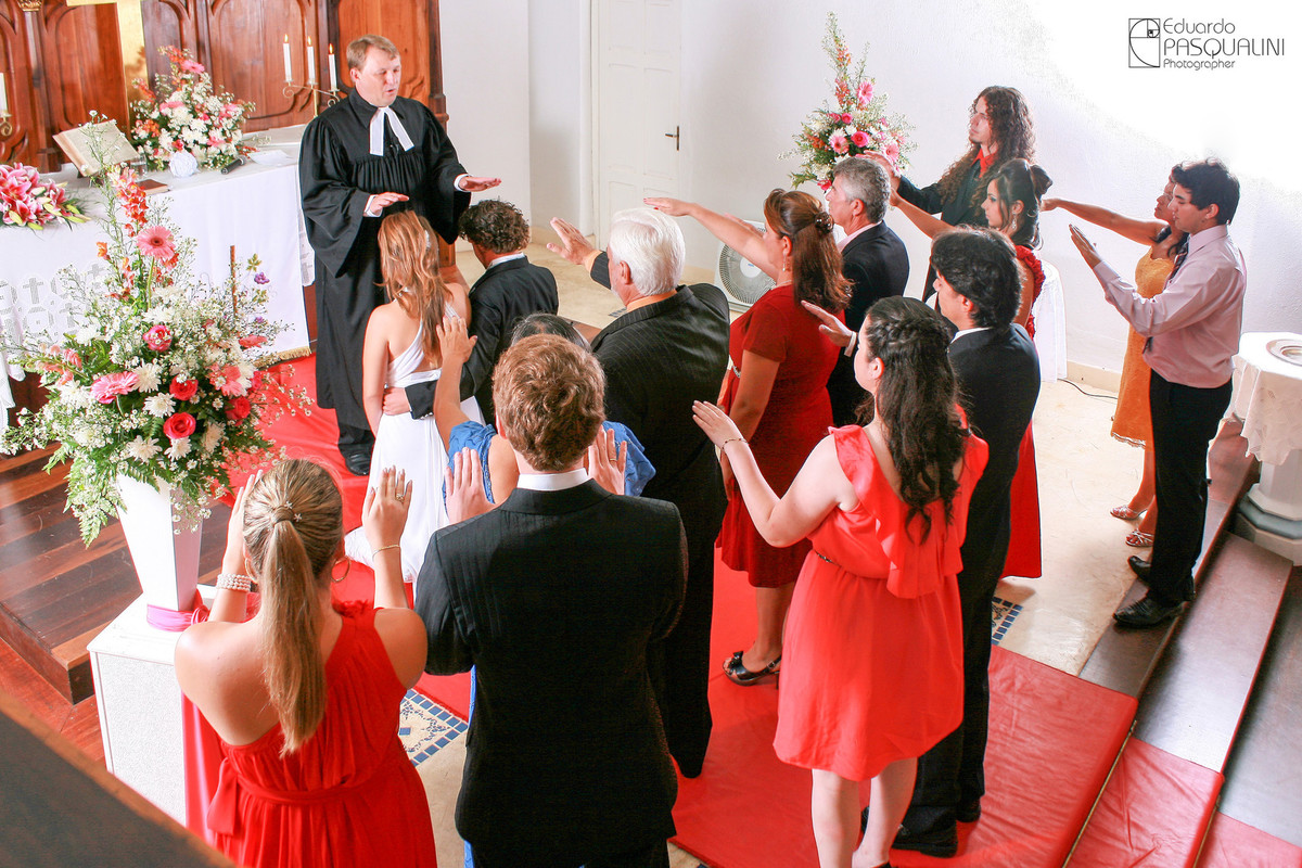 Pais e Padrinhos de mãos erguidas durante benção. Fotografia de Eduardo Pasqualini, fotógrafo de casamentos e ensaios em Rio do Sul, Santa Catarina.