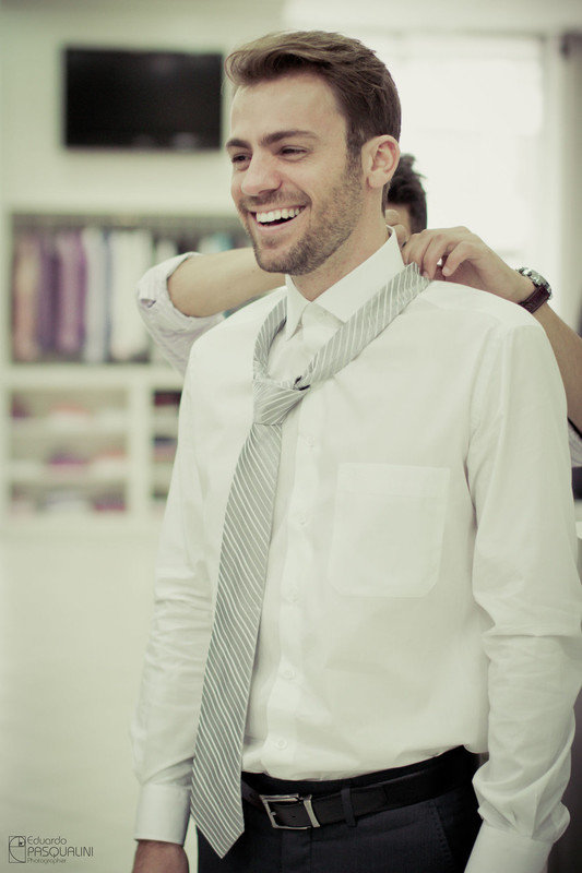 Colocando a gravata no noivo durante o making of. Fotografia de Eduardo Pasqualini, fotógrafo de casamentos e ensaios em Rio do Sul, Santa Catarina.