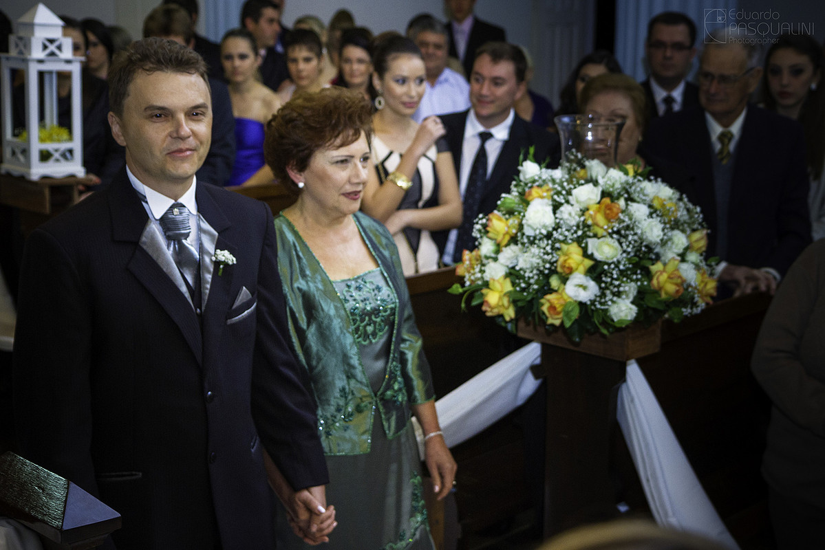 Noivo entrando em seu casamento junto de sua mãe de mãos dadas. Fotografia de Eduardo Pasqualini, fotógrafo de casamentos e ensaios em Rio do Sul, Santa Catarina.