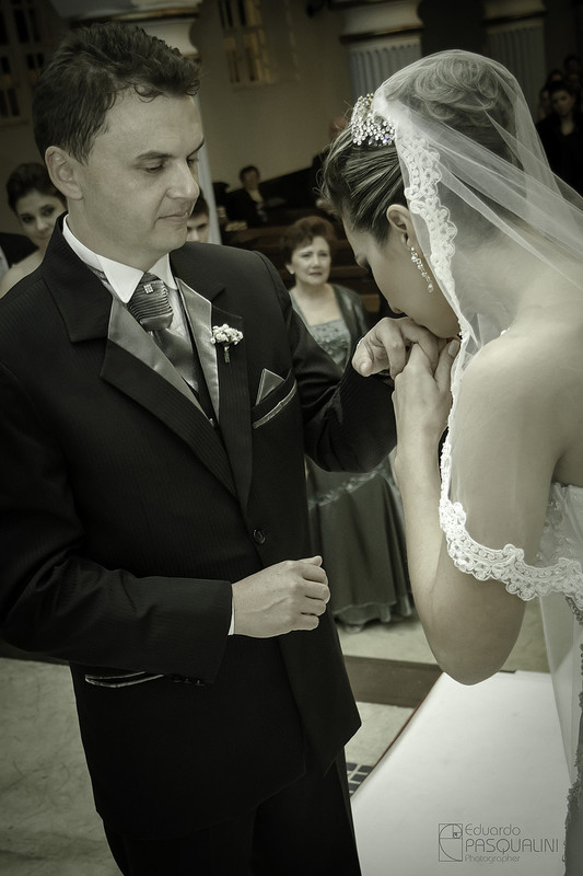 A noiva Joyce beijando a mão do noiva Roberto durante a cerimônia. Fotografia de Eduardo Pasqualini, fotógrafo de casamentos e ensaios em Rio do Sul, Santa Catarina.