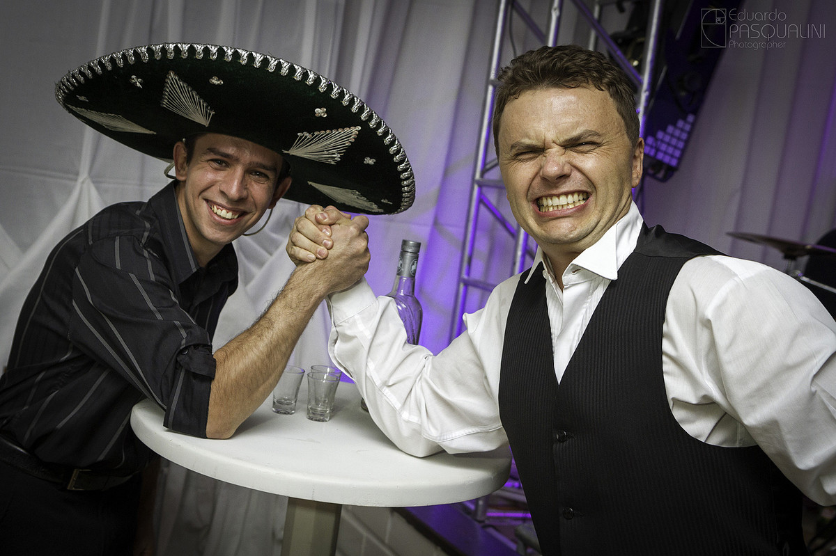Se divertindo com tequileiro, noivo Roberto faz queda de braço. Fotografia de Eduardo Pasqualini, fotógrafo de casamentos e ensaios em Rio do Sul, Santa Catarina.