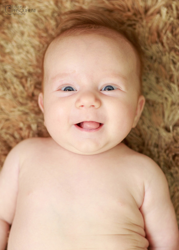 Risonho, bebe sorrindo para a câmera. Fotografia de Eduardo Pasqualini, fotógrafo de casamentos e ensaios em Rio do Sul, Santa Catarina.