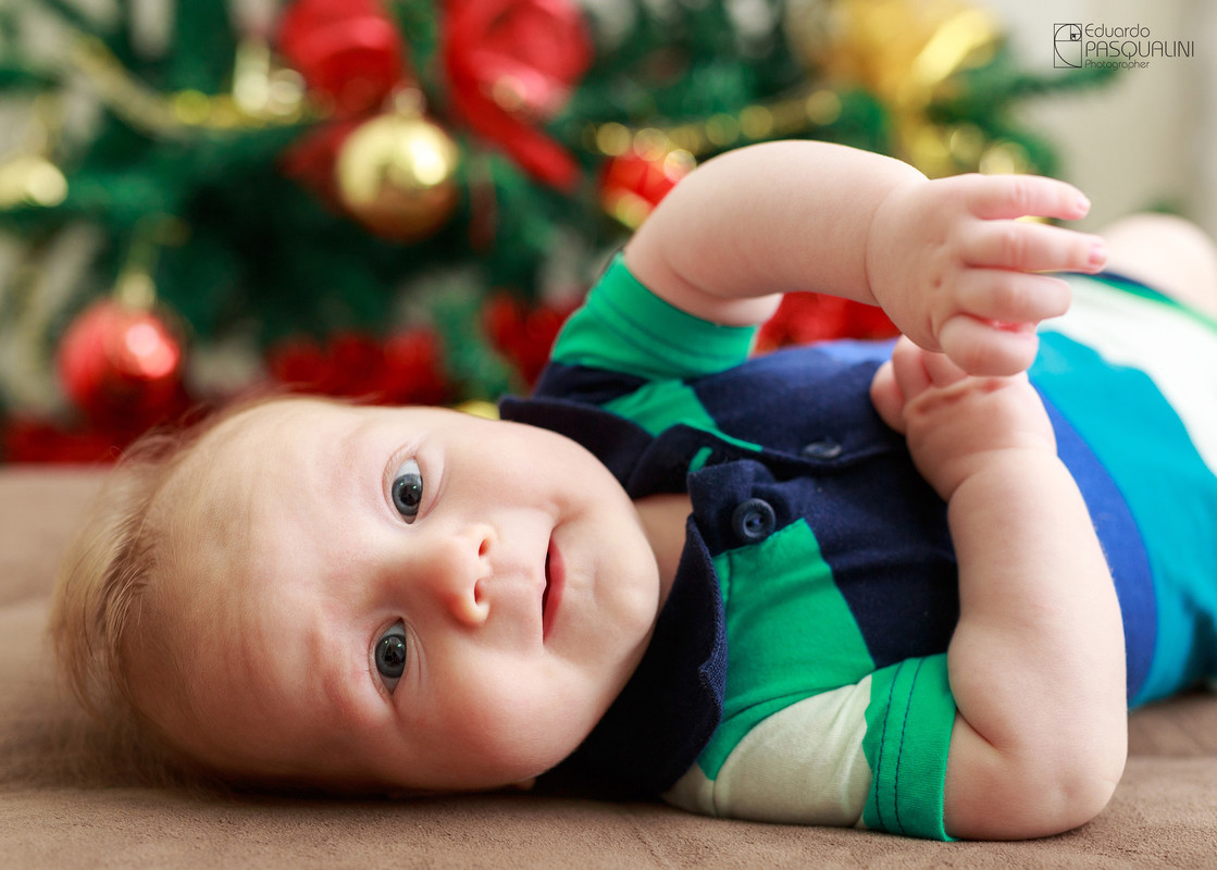 Foto de bebe próximo a árvore de natal. Fotografia de Eduardo Pasqualini, fotógrafo de casamentos e ensaios em Rio do Sul, Santa Catarina.