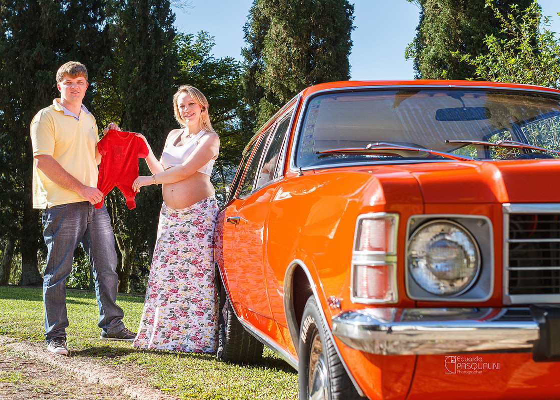 Segurando a roupinha de bebe junto a uma Caravam 4100. Fotografia de Eduardo Pasqualini, fotógrafo de casamentos e ensaios em Rio do Sul, Santa Catarina.