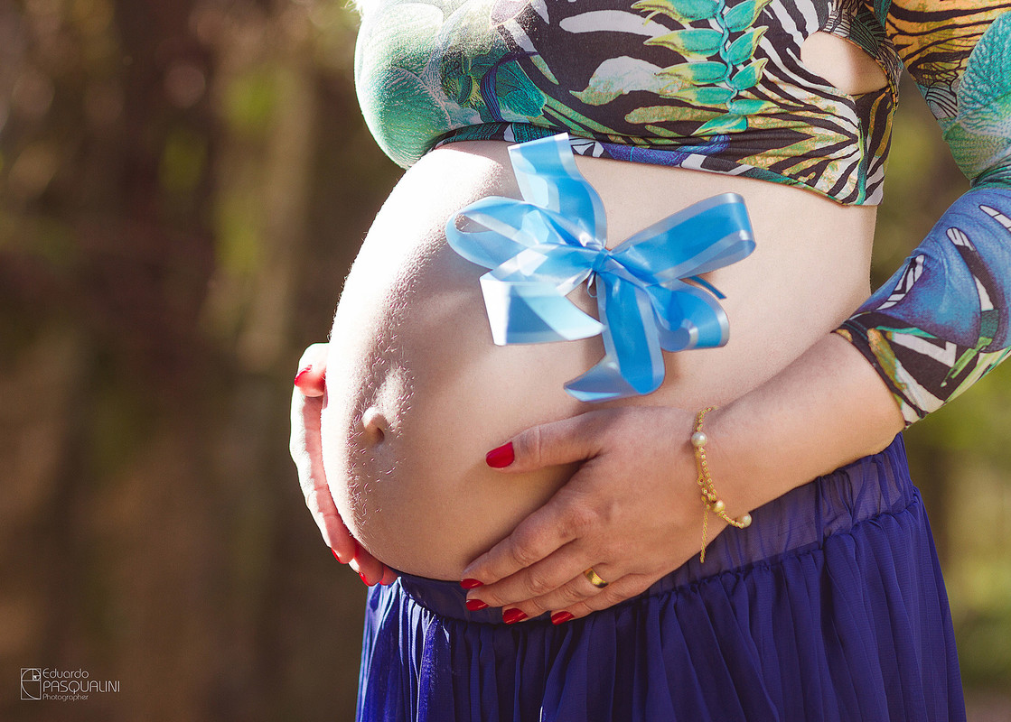 Barriga de gestante com laço azul. Fotografia de Eduardo Pasqualini, fotógrafo de casamentos e ensaios em Rio do Sul, Santa Catarina.