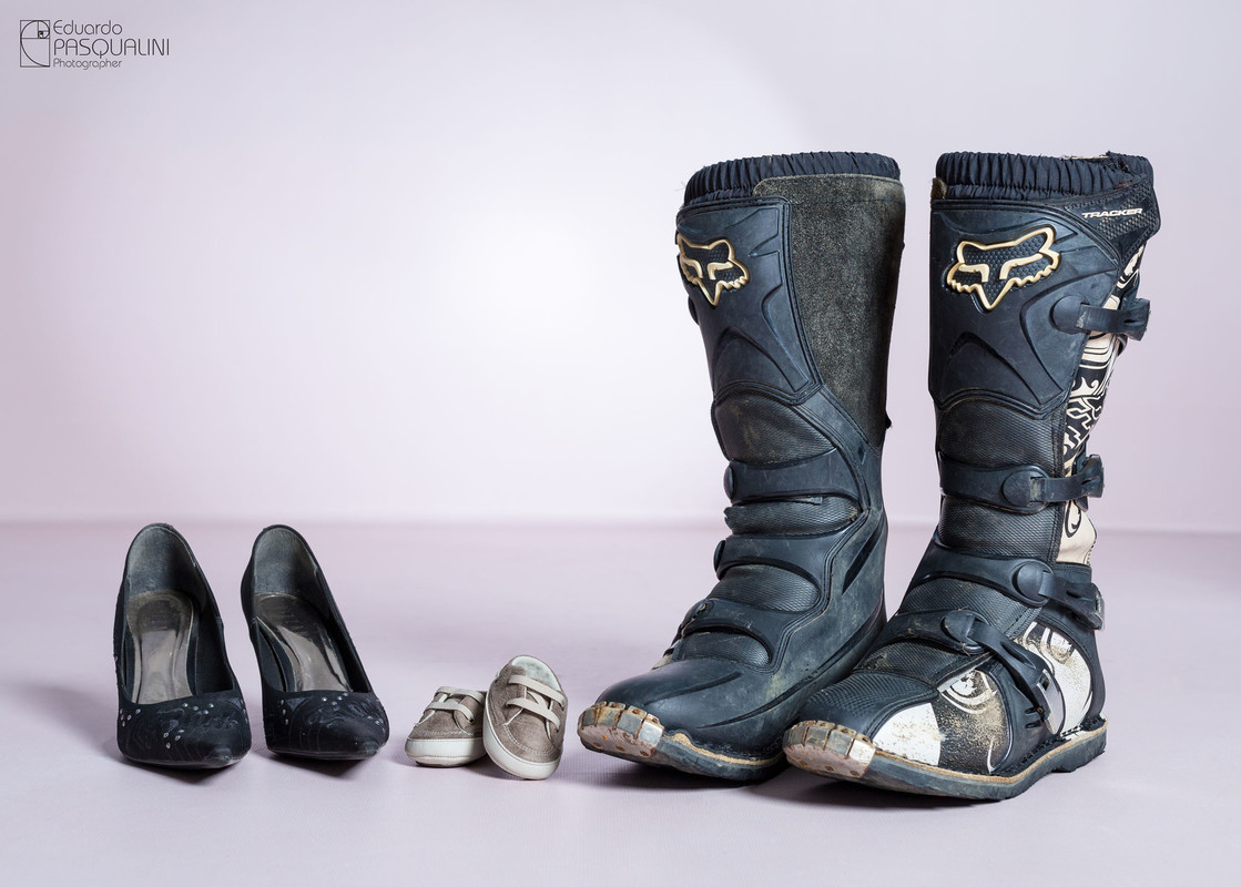 Sapato da mãe, sapato do bebe e bota do pai piloto de moto. Ensaio de Gestante. Fotografia de Eduardo Pasqualini, fotógrafo de casamentos e ensaios em Rio do Sul, Santa Catarina.
