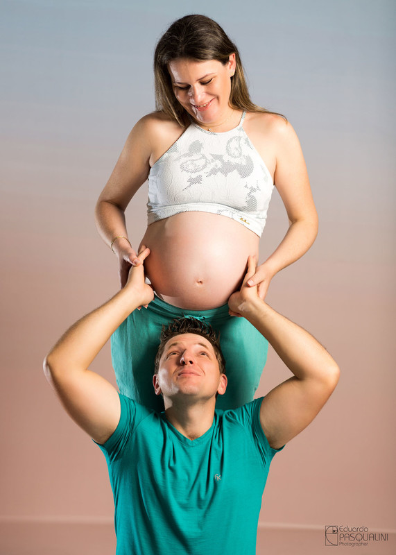 Gravides bem humorada com papai segurando a barriga da mãe. Ensaio de Gestante. Fotografia de Eduardo Pasqualini, fotógrafo de casamentos e ensaios em Rio do Sul, Santa Catarina.