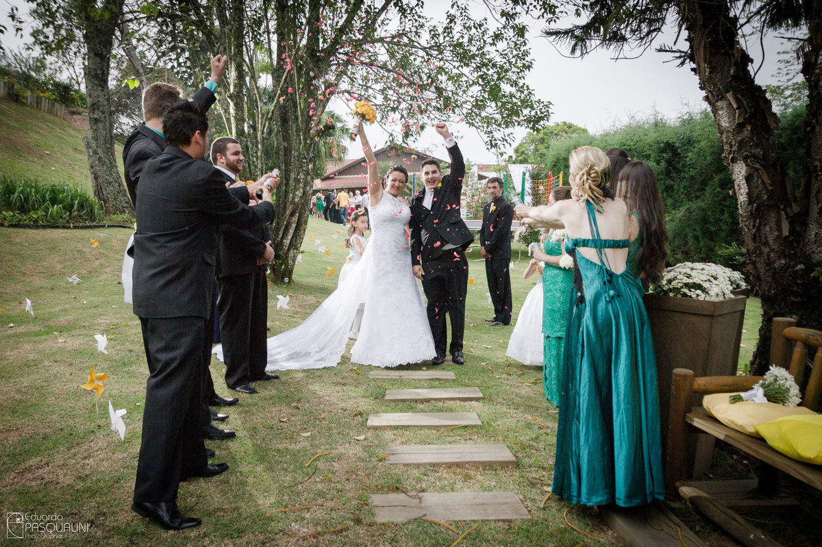 Padrinhos jogando pétalas de rosas para os noivos em casamento ao ar livre. Fotografia de Eduardo Pasqualini, fotógrafo de casamentos e ensaios em Rio do Sul, Santa Catarina. Villa Viver.