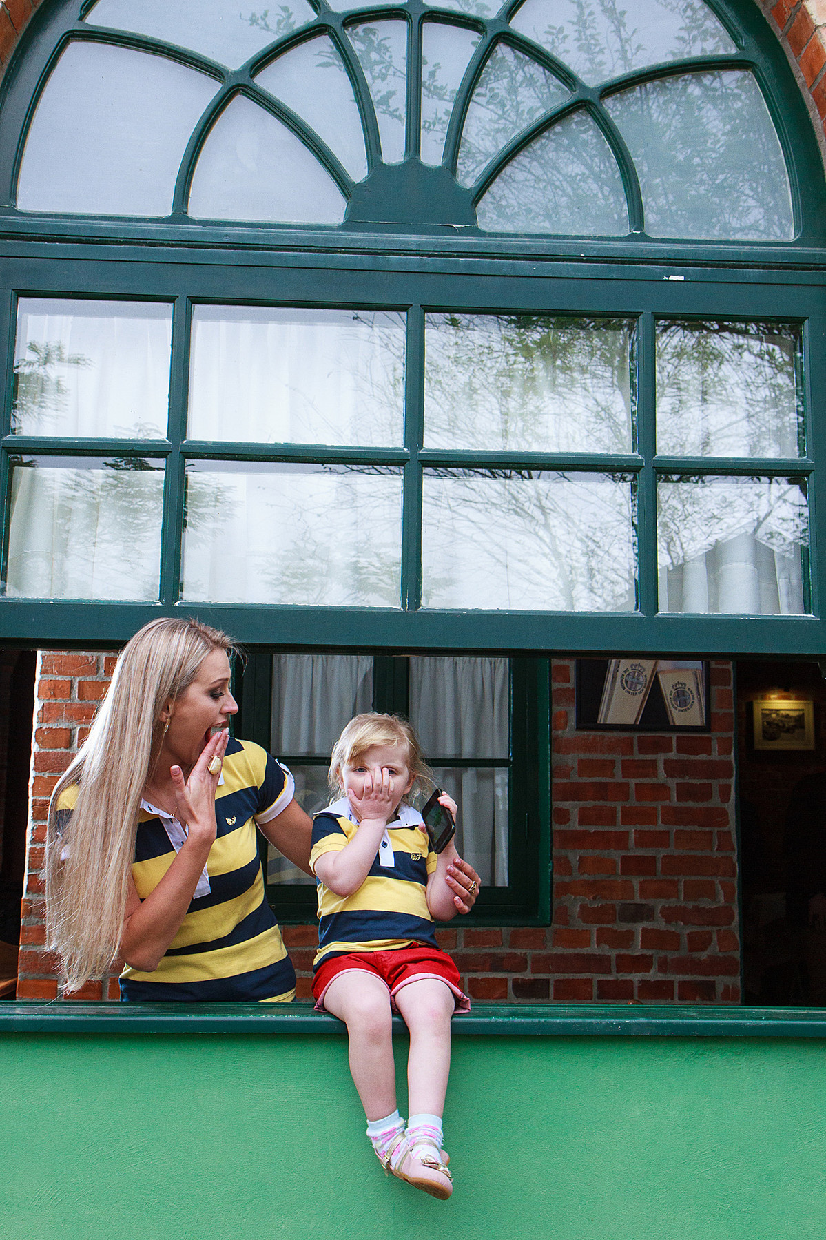 Filha brincando com a mãe na janela. Fotografia de Eduardo Pasqualini, fotógrafo de casamentos e ensaios em Rio do Sul, Santa Catarina.