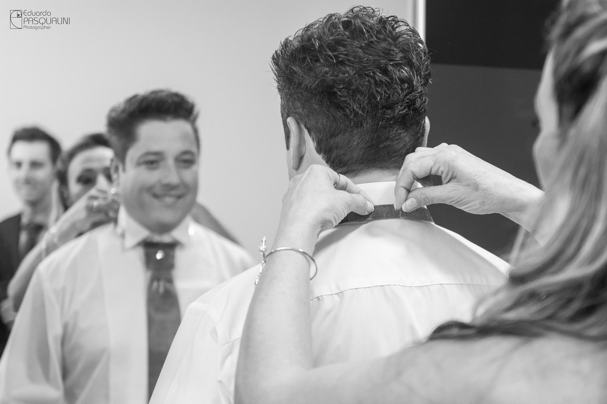 Mãe do noivo ajuda a colocar a gravata. Fotografia de Eduardo Pasqualini, fotógrafo de casamentos e ensaios em Rio do Sul, Santa Catarina.