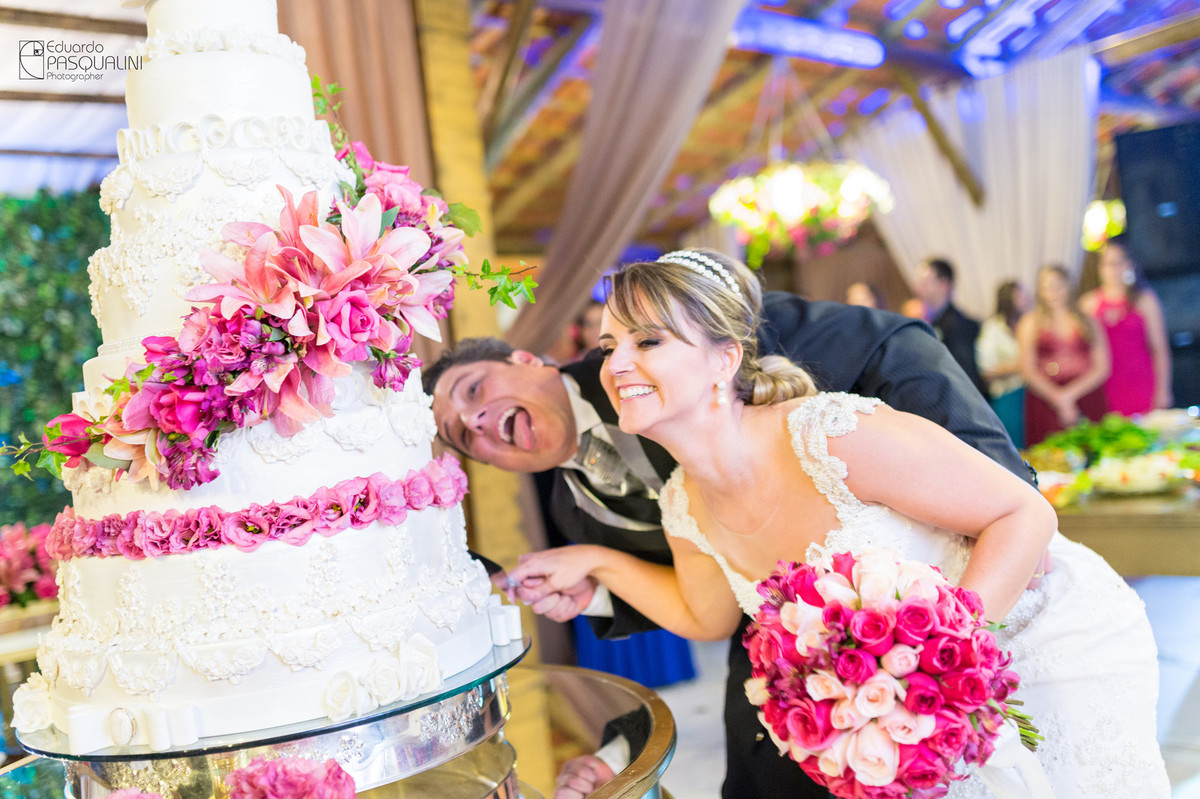 Noivo e noiva brincando com o corte do bolo. Fotografia de Eduardo Pasqualini, fotógrafo de casamentos e ensaios em Rio do Sul, Santa Catarina.