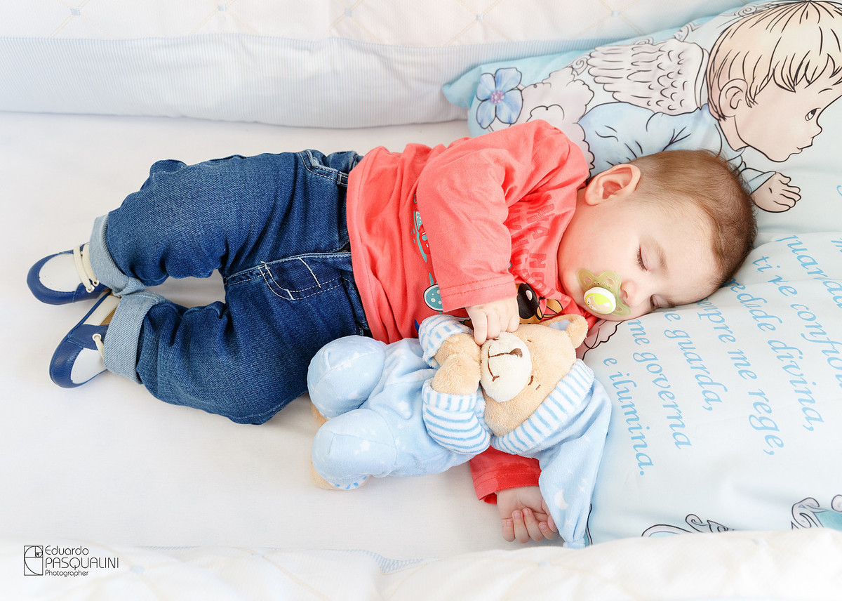 Bebe dormindo junto com ursinho de pelúcia. Fotografia de Eduardo Pasqualini, fotógrafo de casamentos e ensaios em Rio do Sul, Santa Catarina.