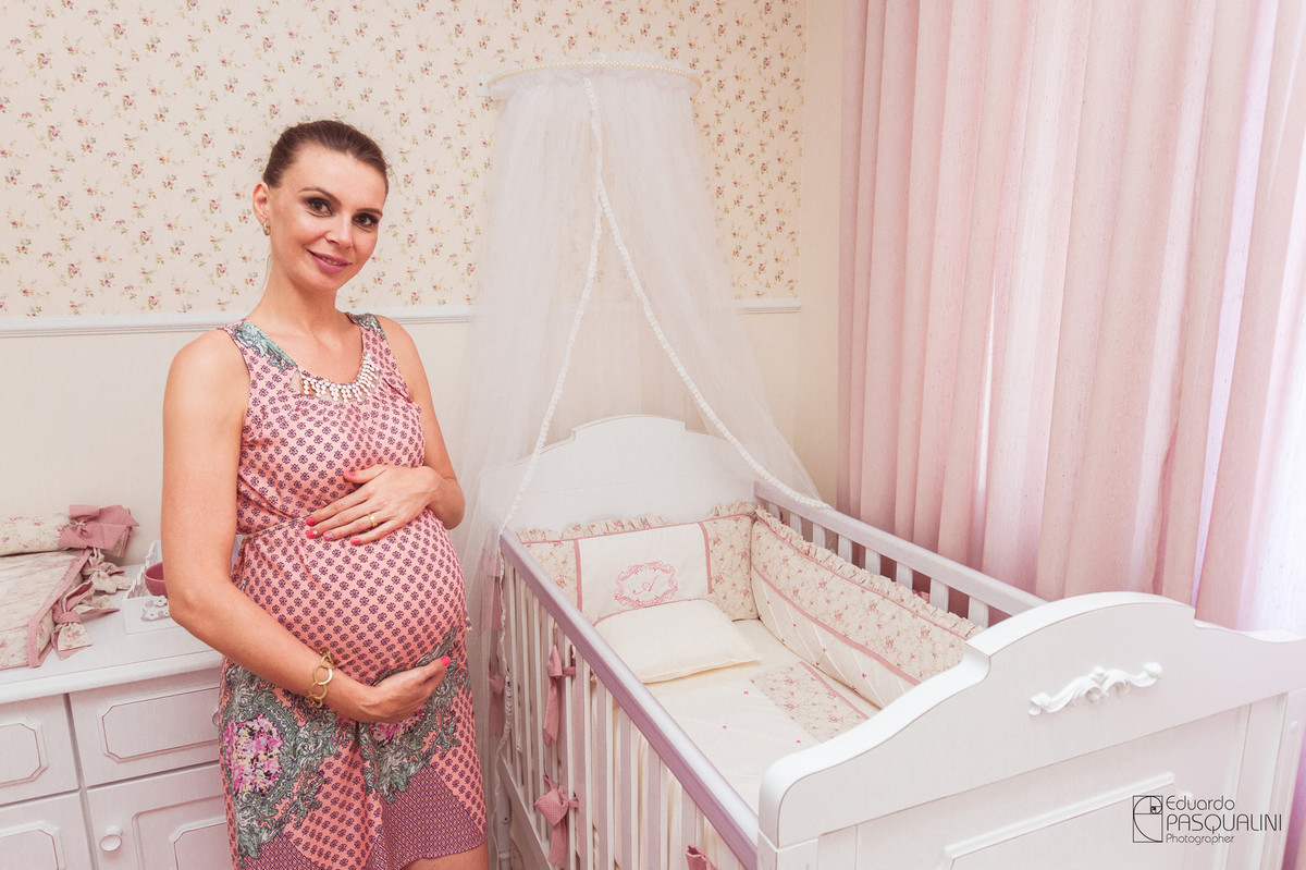 Mamãe Ângela feliz ao lado do berço da Alícia. Fotografia de Eduardo Pasqualini, fotógrafo de casamentos e ensaios em Rio do Sul, Santa Catarina.