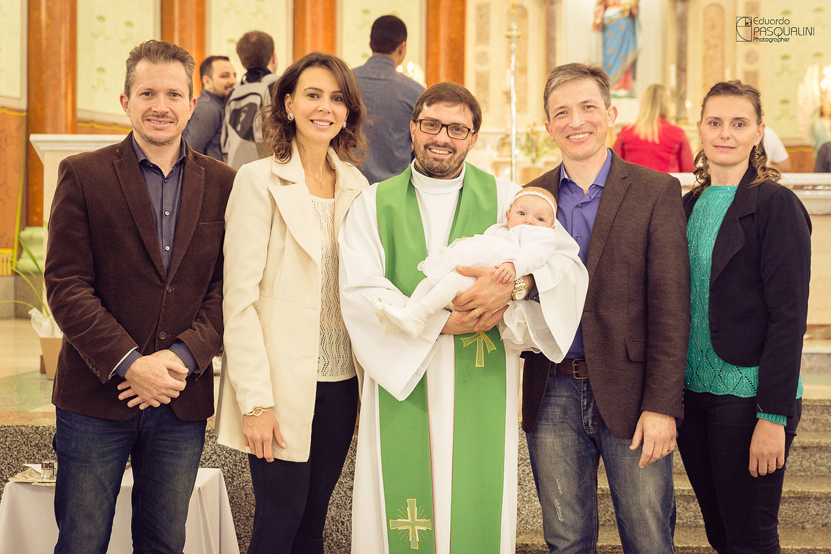 Padre segurando bebê Alícia junto de pais e padrinhos. Fotografia de Eduardo Pasqualini, fotógrafo de casamentos e ensaios em Rio do Sul, Santa Catarina.
