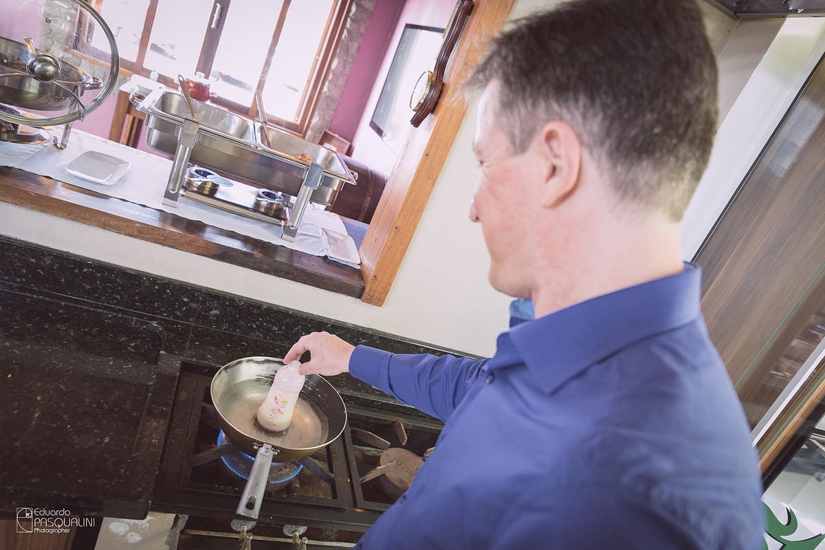 Papai Anderson esquentando a mamadeira da Alícia. Osteria La Campagnaga. Fotografia de Eduardo Pasqualini, fotógrafo de casamentos e ensaios em Rio do Sul, Santa Catarina.
