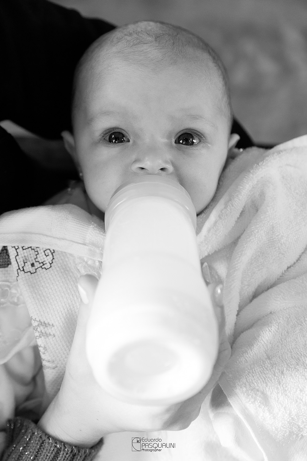 Alícia tomando tranquilamente sua mamadeira. Osteria La Campagnaga. Fotografia de Eduardo Pasqualini, fotógrafo de casamentos e ensaios em Rio do Sul, Santa Catarina.