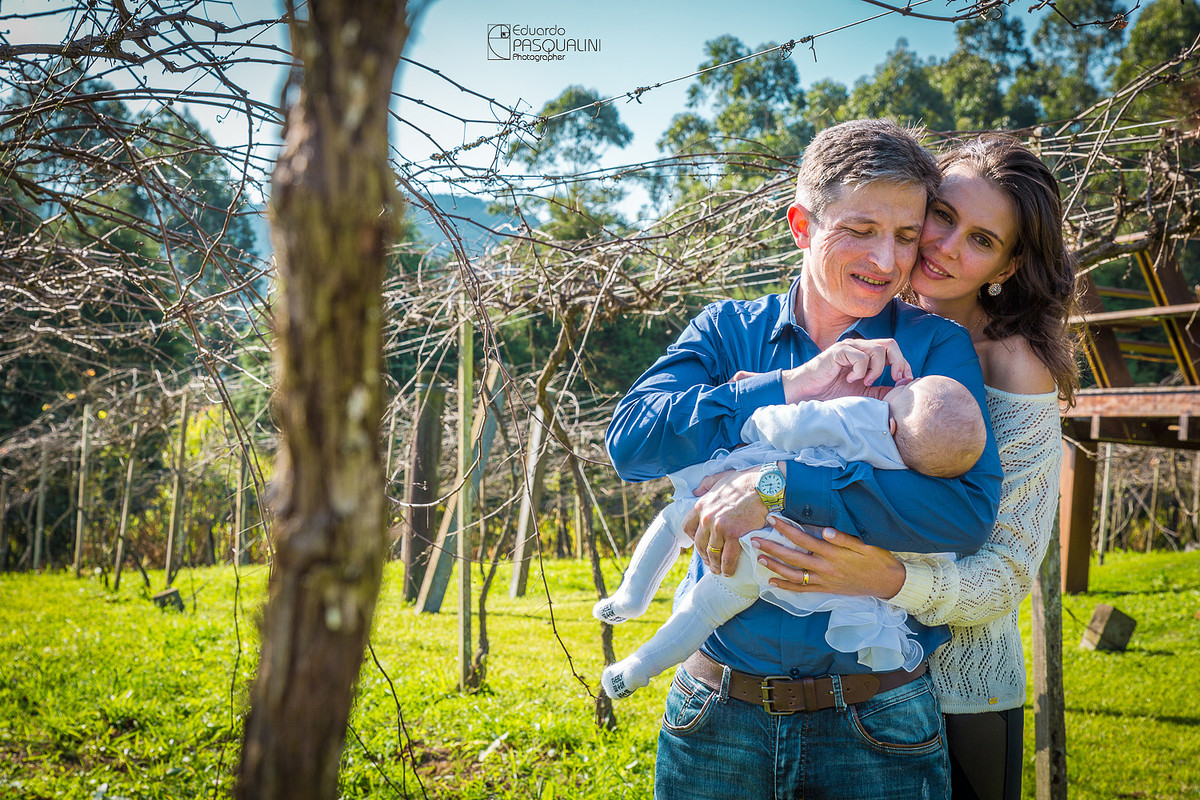 Anderson brincando com bebê Alícia em meio da parreiral de uvas.Osteria La Campagnaga. Fotografia de Eduardo Pasqualini, fotógrafo de casamentos e ensaios em Rio do Sul, Santa Catarina.