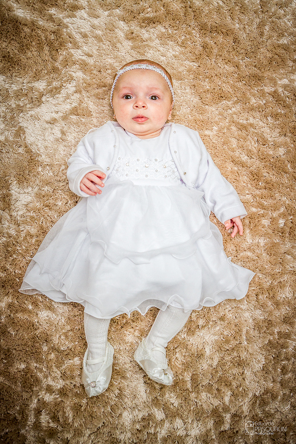 Bebê Alícia deitada em tapete texturizado. Fotografia de Eduardo Pasqualini, fotógrafo de casamentos e ensaios em Rio do Sul, Santa Catarina.