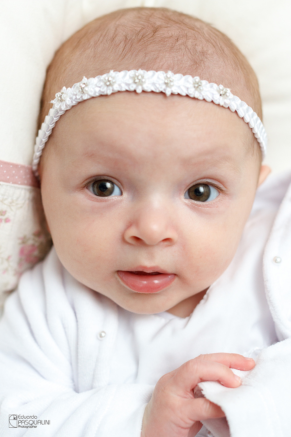 Linda criança bebê Alícia, com sua fita de florzinhas e vestido do dia do Batizado. Fotografia de Eduardo Pasqualini, fotógrafo de casamentos e ensaios em Rio do Sul, Santa Catarina.