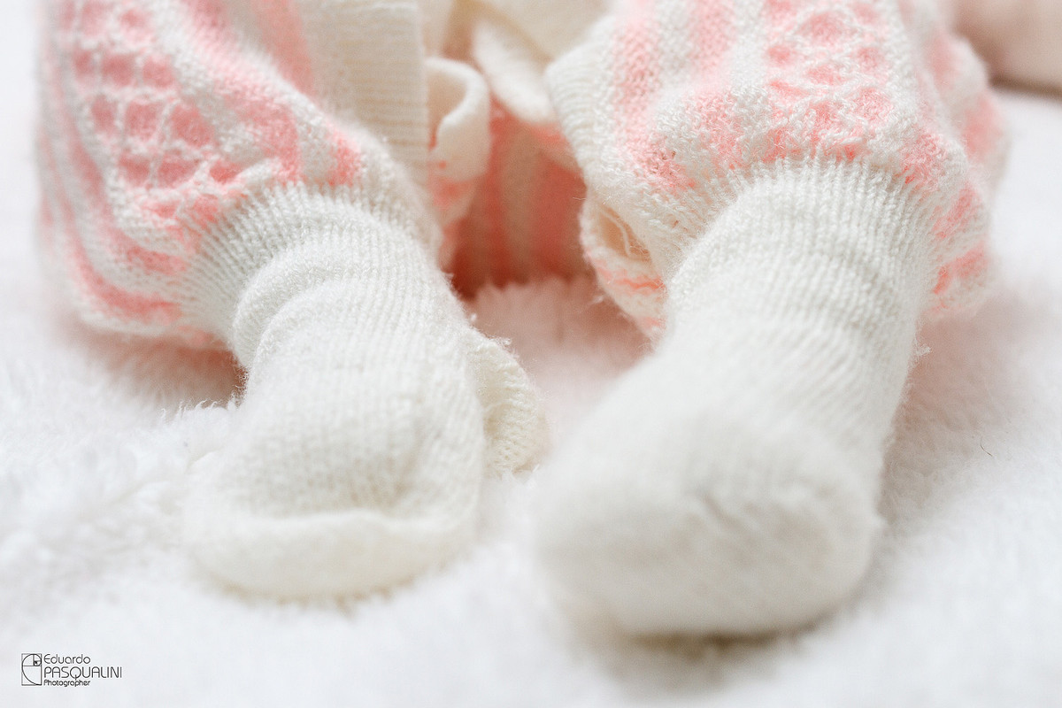 Detalhe dos pés do bebê Alícia que veste a roupa de bebê de sua mãe. Fotografia de Eduardo Pasqualini, fotógrafo de casamentos e ensaios em Rio do Sul, Santa Catarina.