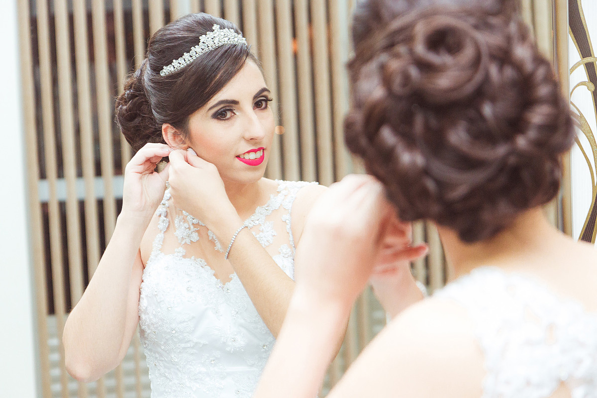 Colocando brincos, noiva se arrumando para casamento. Eduardo Pasqualini Fotografias - Fotógrafo profissional de ensaio e casamento em Rio do Sul, Santa Catarina, Brasil.