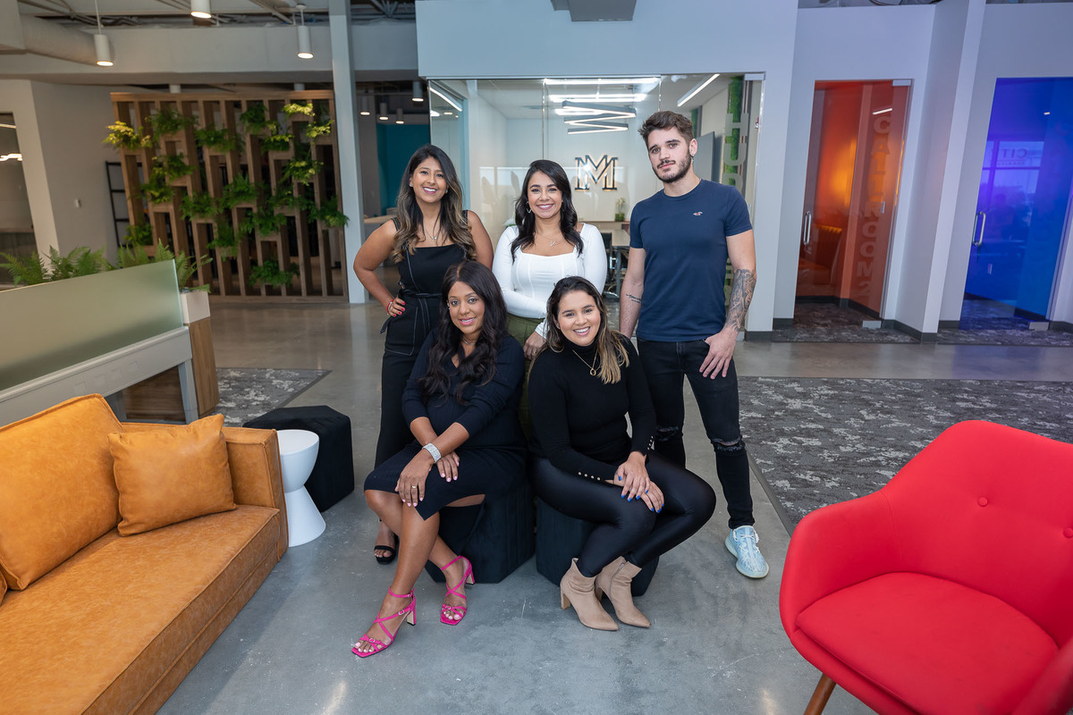 Portrait of a professional team in a modern office setting in Orlando, FL, featuring a stylish interior design ideal for real estate and interior photography. The setting features a vibrant mix of furniture and natural design elements.