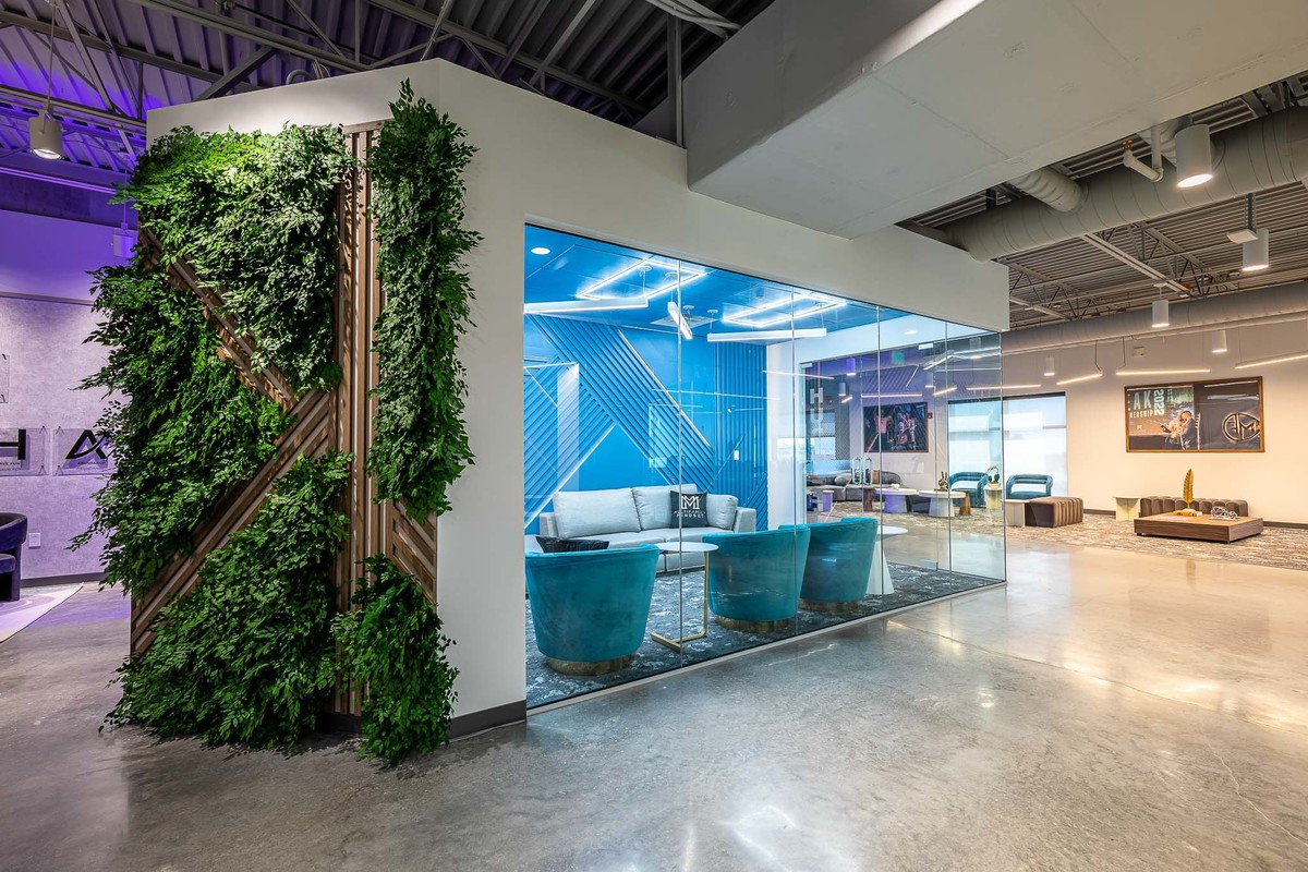 Modern office space in Orlando, FL, perfect for interior and real estate photography. Highlights a glass-walled meeting room with sleek furnishings, complemented by a living wall of plants. Ideal for real estate portfolios