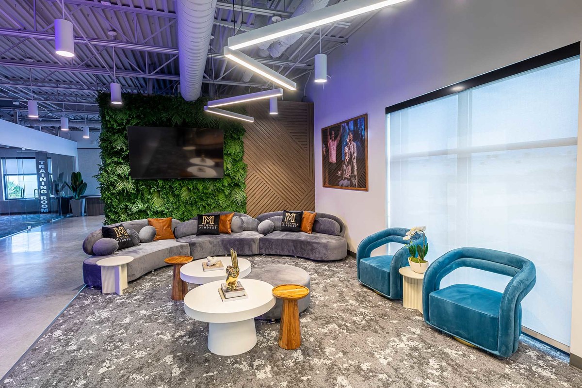 Inviting office lounge in Orlando, FL featuring a modern design ideal for interior and real estate photography. Features a living green wall, chic furniture, and dynamic lighting, perfect for enhancing property portfolios.