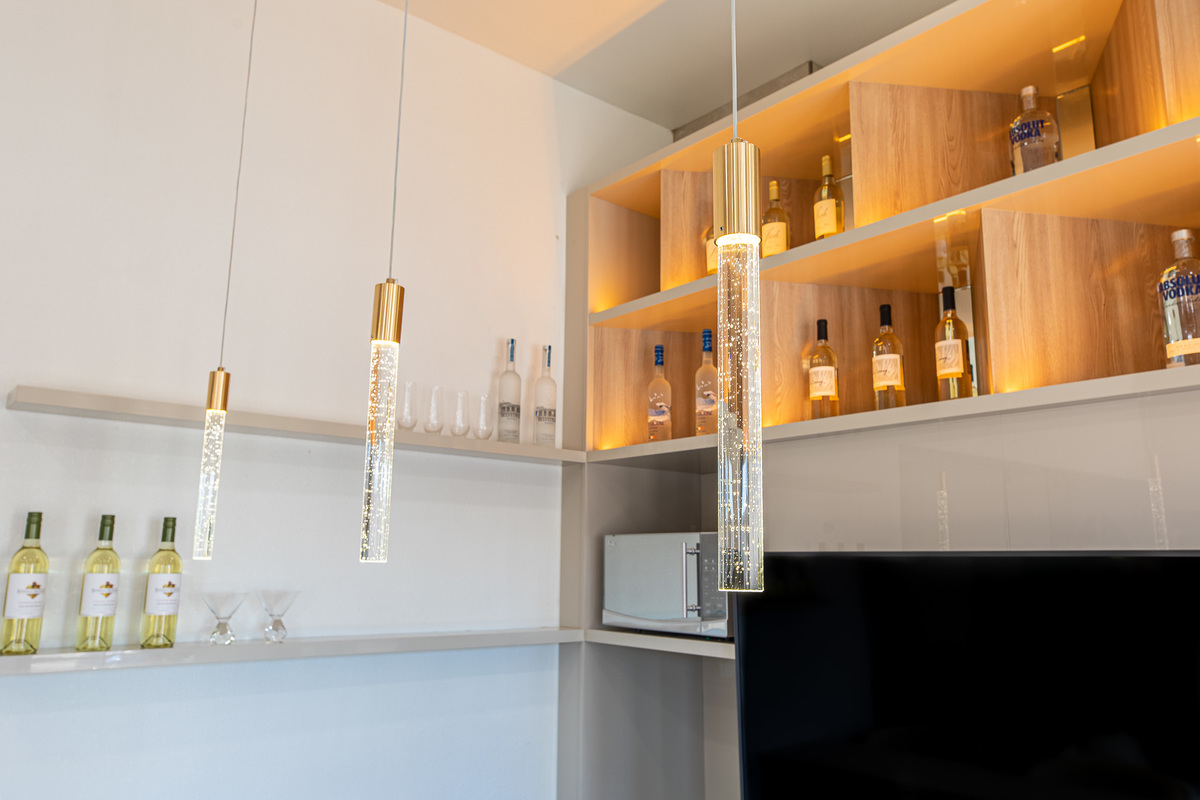 Modern bar area with elegant wooden stools, sleek shelves, and premium lighting, highlighting sophisticated interior design and architectural details.