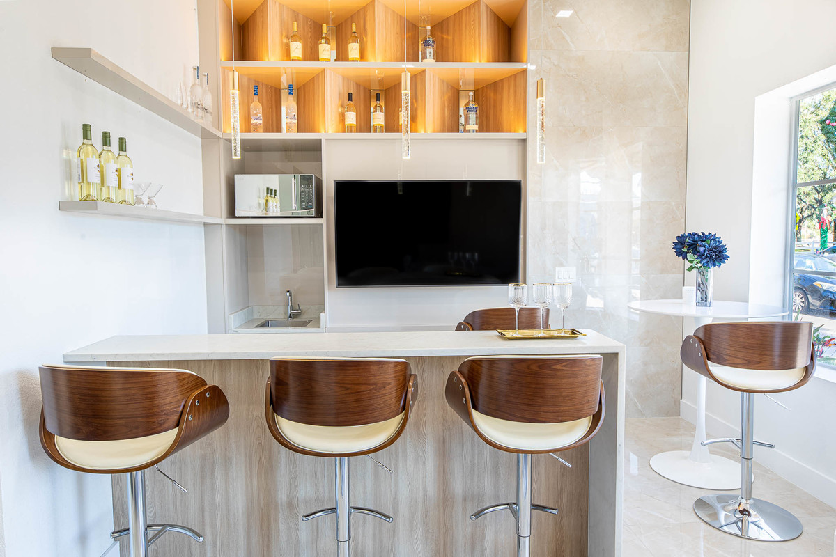 Modern bar area with elegant wooden stools, sleek shelves, and premium lighting, highlighting sophisticated interior design and architectural details.