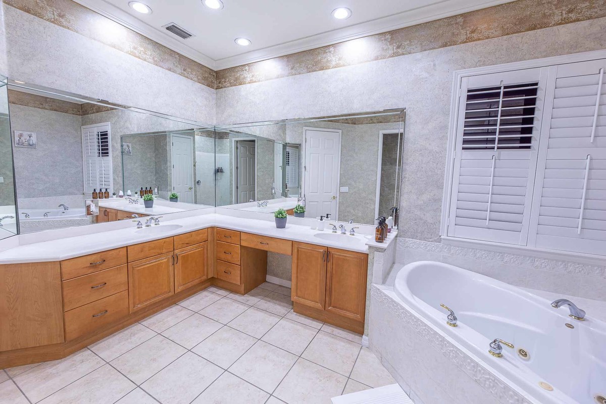 Large, mirrored bathroom with elegant wood cabinetry, expertly photographed to enhance the interior details in Orlando.