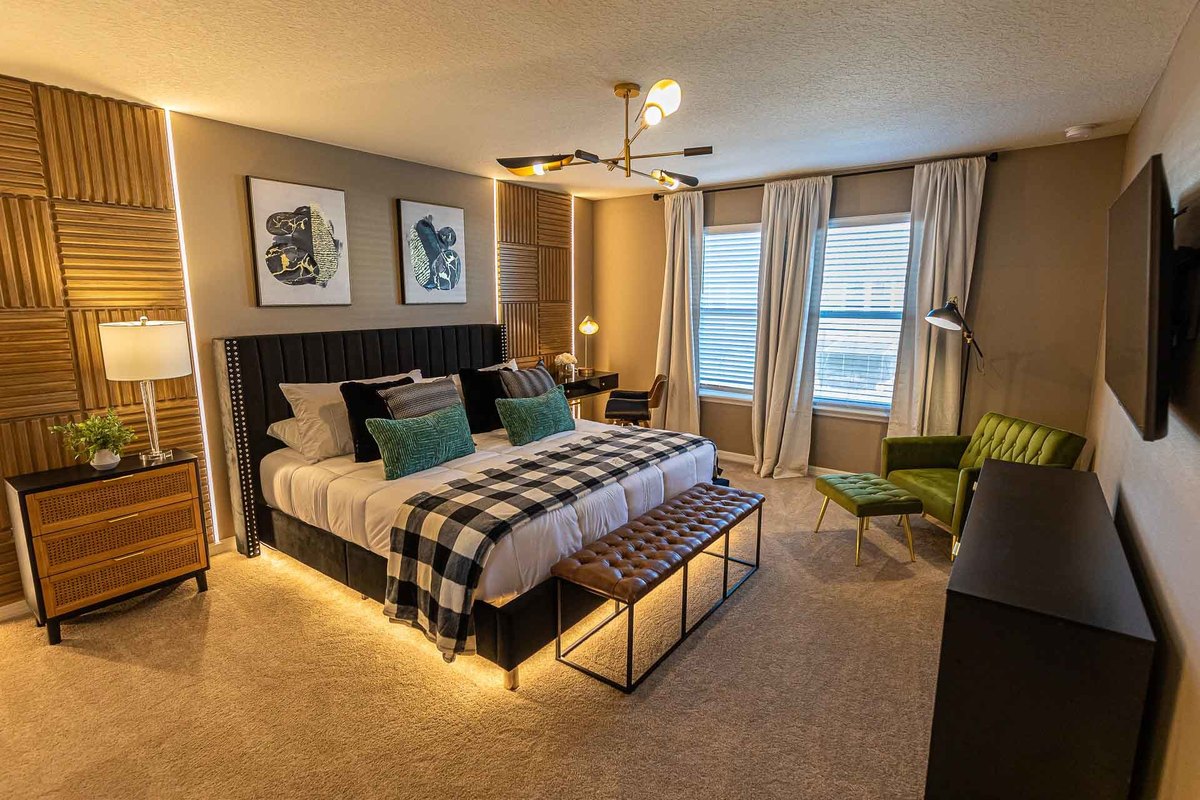 Elegant Master Suite: This interior photograph shows a master suite decorated with a harmony of wood and fabrics, featuring a neutral color scheme with touches of emerald green, creating a refined and welcoming environment.