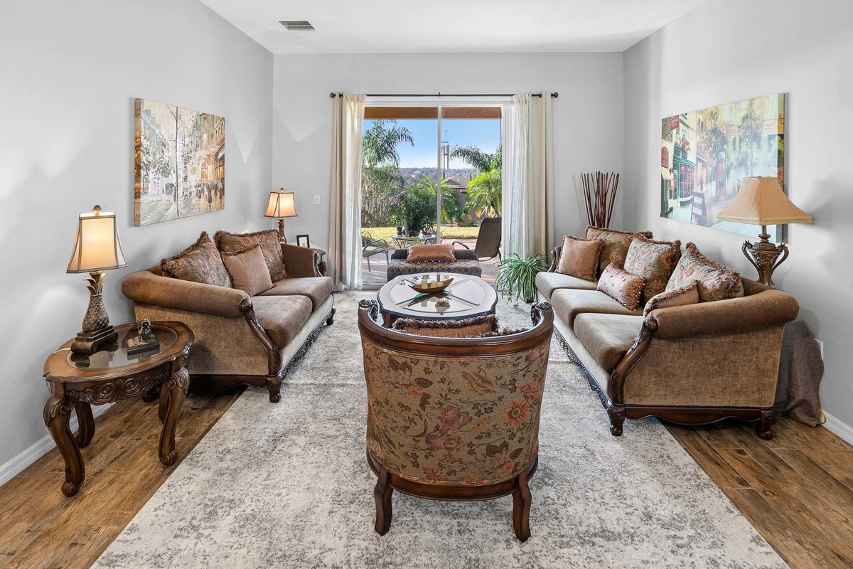 Spacious living room in Clermont, Florida, with abundant natural light, elegant flooring, and an open layout that seamlessly connects spaces, ideal for comfort and family gatherings. Magic Lens Photo Media Real Estate Photography.