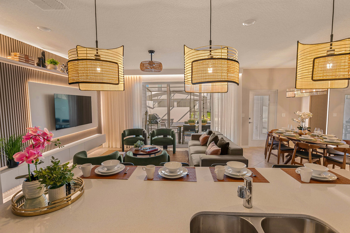 Interior view of a modern living-dining area featuring woven pendant lights, green chairs, and a set table. Real Estate and Interior Photography by Magic Lens Photo Media.