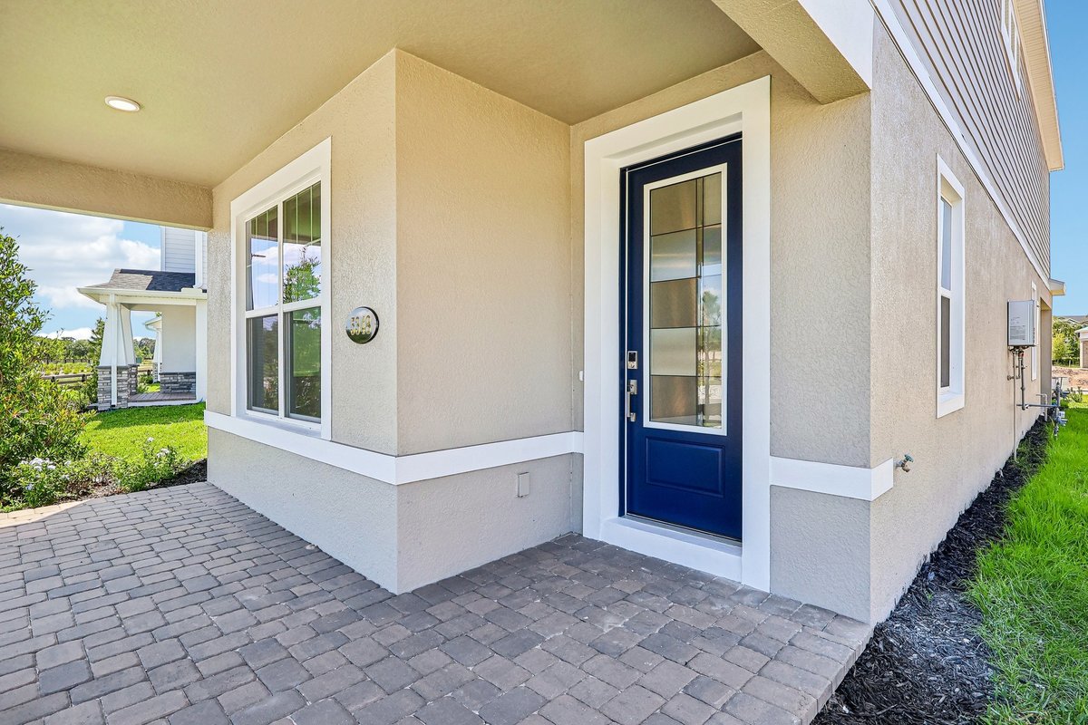 covered-front-porch-entry-navy-blue-glass-door-paver-walkway-stucco-exterior-new-home-5348-ctr-lk-rnch-blvd-st-cloud-fl