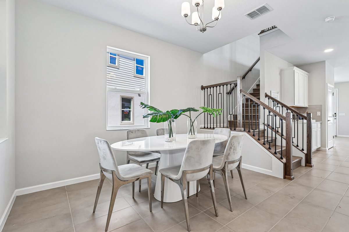 elegant-dining-room-white-round-table-velvet-chairs-chandelier-iron-staircase-railing-5348-ctr-lk-rnch-blvd-st-cloud-fl