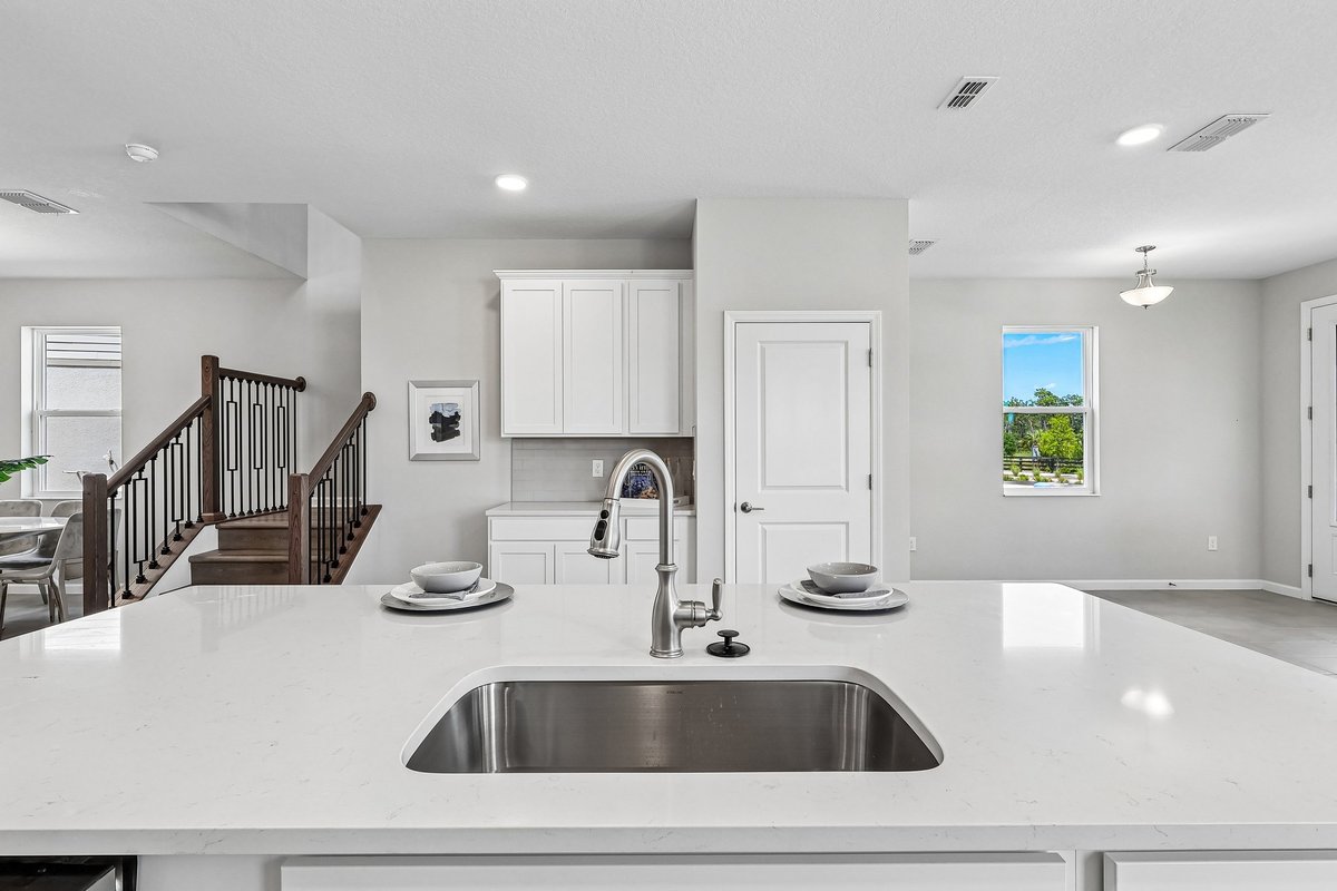kitchen-island-close-up-quartz-countertop-stainless-sink-staircase-view-open-layout-5348-ctr-lk-rnch-blvd-st-cloud-fl