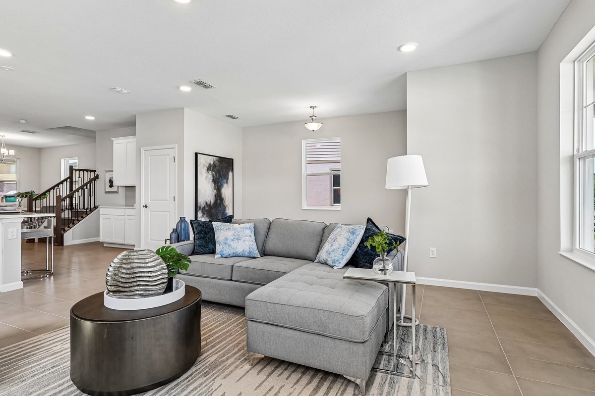 modern-living-room-gray-sectional-sofa-blue-pillows-abstract-wall-art-staircase-view-5348-ctr-lk-rnch-blvd-st-cloud-fl