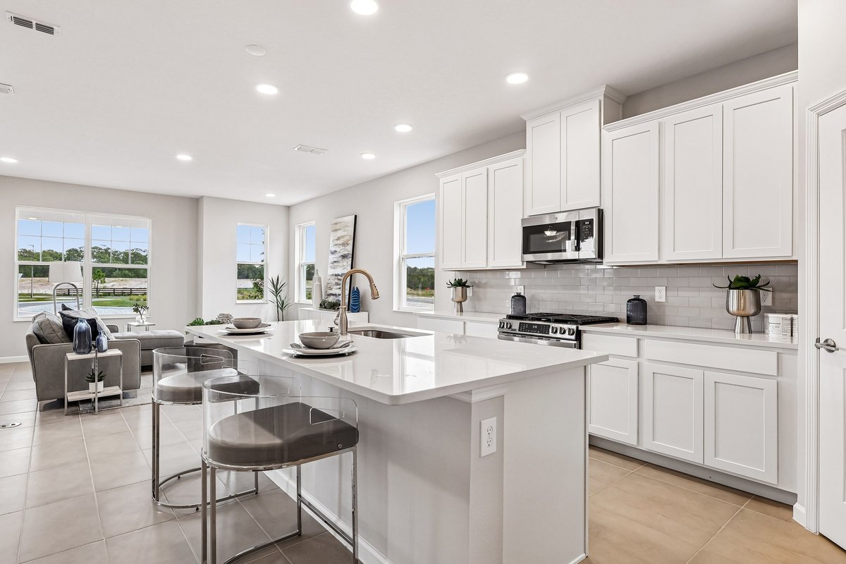 open-kitchen-living-room-white-cabinets-quartz-island-gold-faucet-large-windows-natural-light-5348-ctr-lk-rnch-blvd-st-cloud-fl