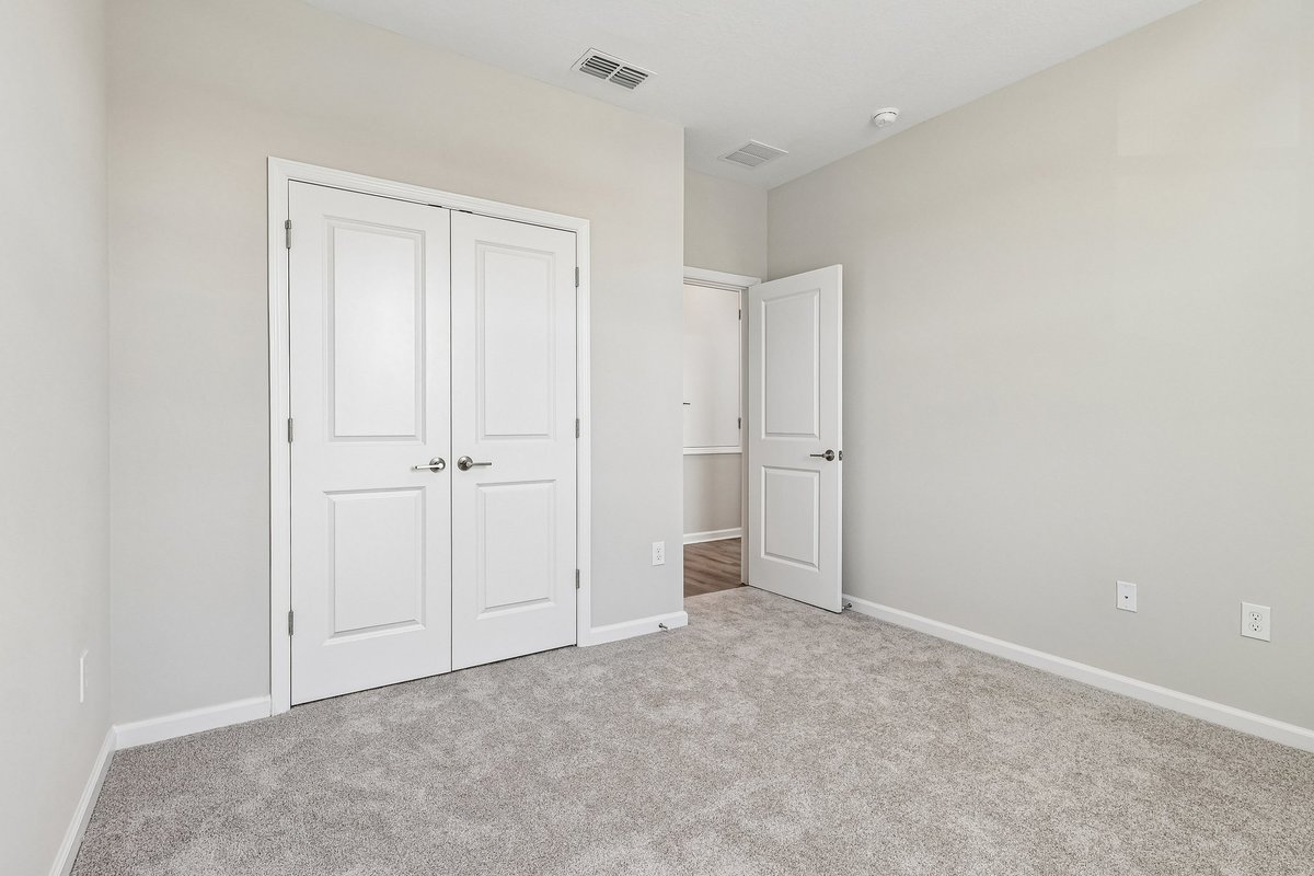 upstairs-bedroom-double-closet-doors-carpet-flooring-neutral-walls-open-door-hallway-5348-ctr-lk-rnch-blvd-st-cloud-fl
