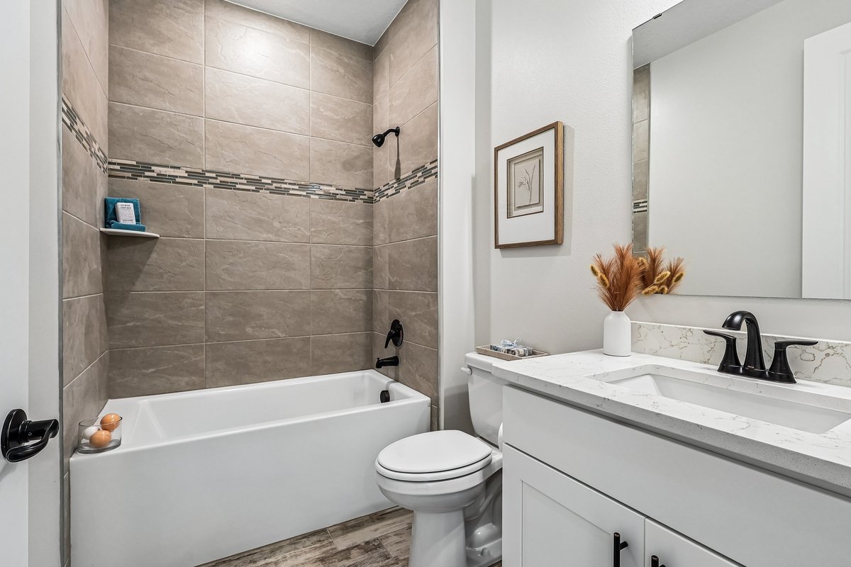Bathroom with tub shower, tile wall, and white vanity in Palm Bay FL home