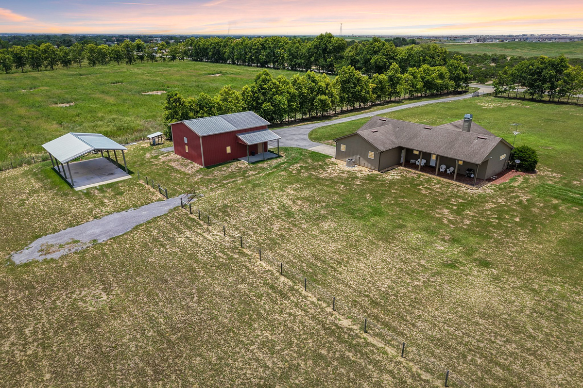 Aerial view of acreage property in Haines City with custom home, red workshop, RV storage, and open land